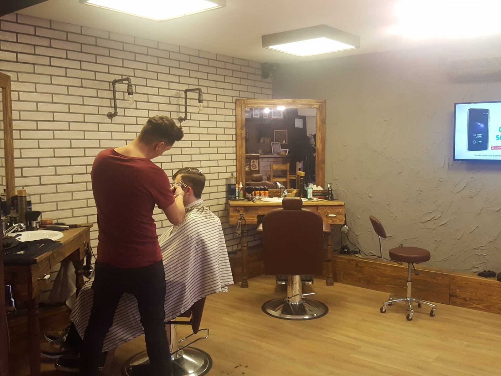 Frizer la lucru la un post din lemn, cu oglindă înrămată