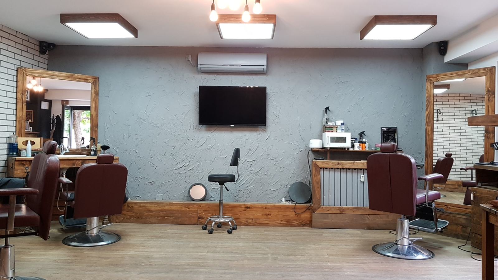 Interiorul frizeriei cu scaune de piele bordo și oglinzi cu ramă de lemn