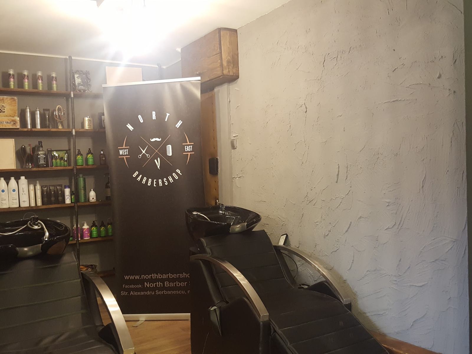 Zona de spălat și rafturile cu produse, cu bannerul North Barbershop