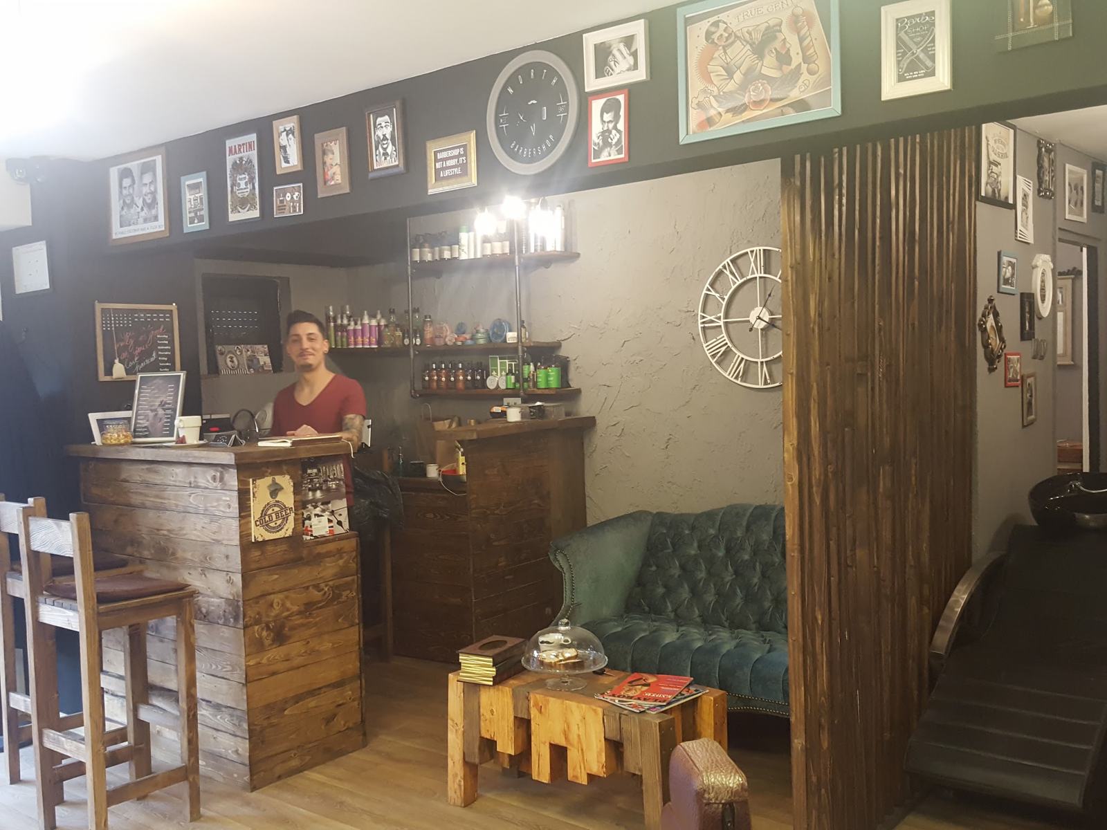 Recepția North Barbershop cu tablouri vintage, ceas de perete și canapea chesterfield